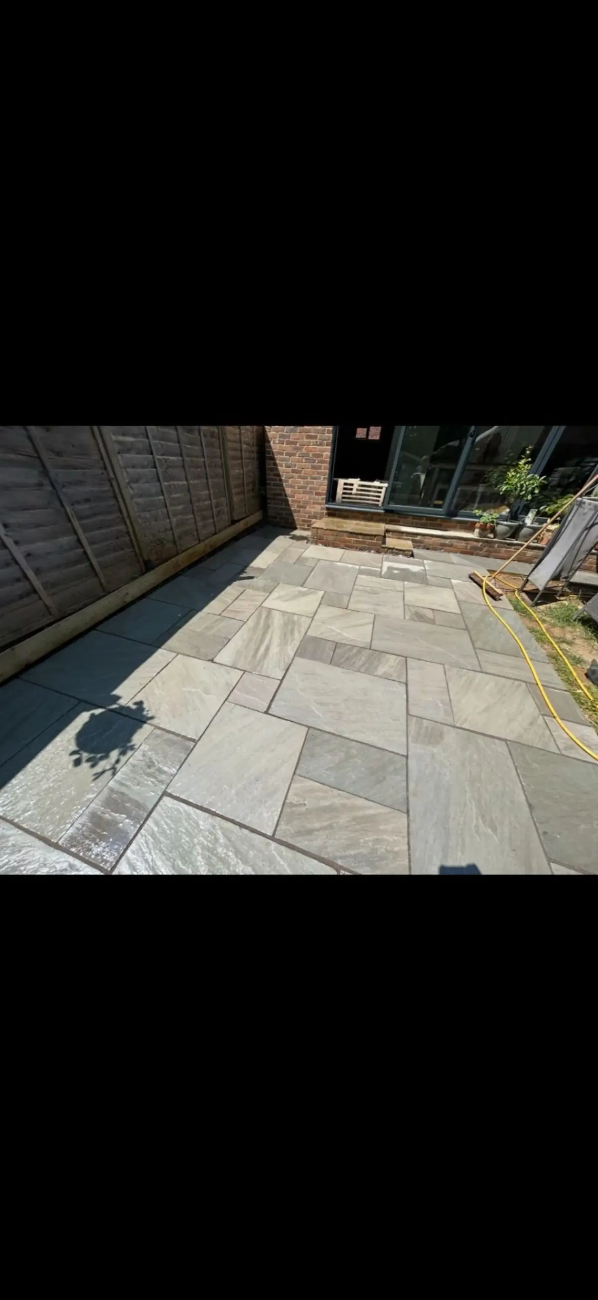 Natural stone patio with fence boundary installed by Burton Builds