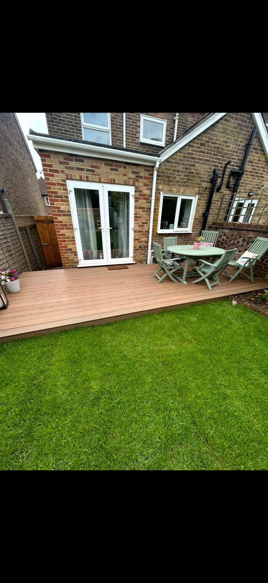 Composite decking with lawn and outdoor dining area by Burton Builds