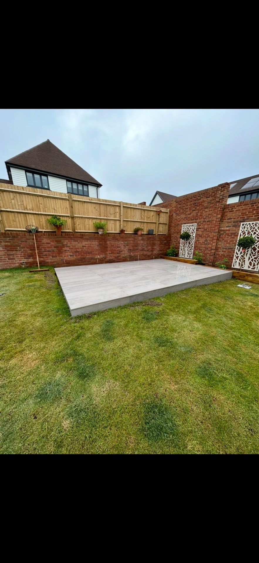 Porcelain patio base with decorative garden screens by Burton Builds